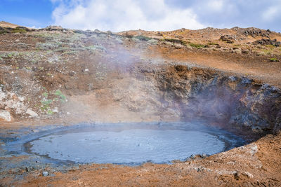 View of geothermal mud spot amidst landscape in hveragerdi valley on sunny day