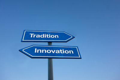 Low angle view of road sign against clear blue sky