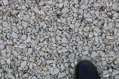 Low section of person standing in pebbles