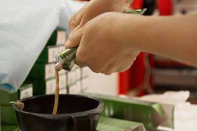 Close-up of hand pouring tea cup