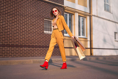 Low angle view of woman with shopping bags walking in city