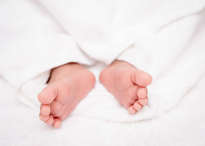 Low section of baby lying on bed