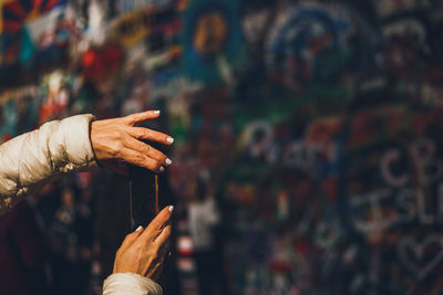 Close-up of hand holding text against wall