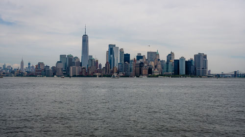 Sea and buildings in city against sky