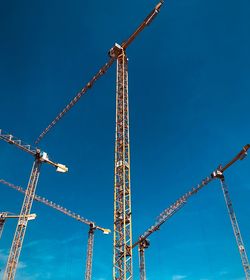 Low angle view of crane against clear blue sky