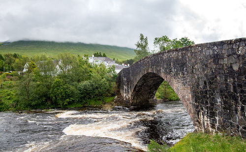 Arch bridge over river against sky