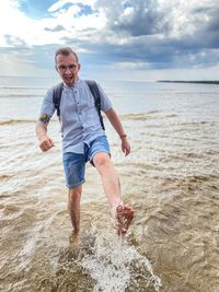 Full length of young man on beach against sky