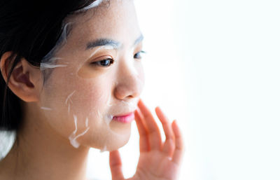 Close-up of young woman against white background