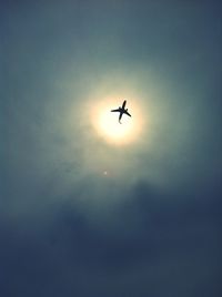 Low angle view of silhouette airplane against cloudy sky