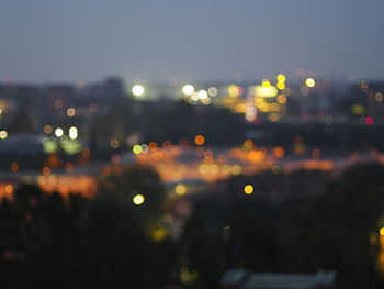 Defocused image of illuminated city against sky at night