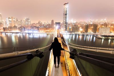 Rear view of man standing by river in city