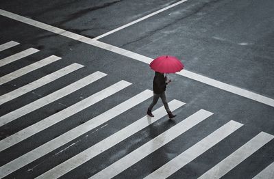 High angle view of woman holding umbrella while walking on road