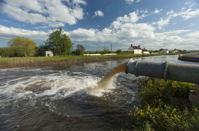 Water flowing from pipe against sky