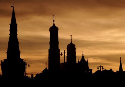 Silhouette of church towers against sky during sunset