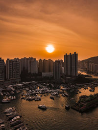 Cityscape by sea against sky during sunset