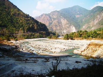 Scenic view of river by mountains against sky