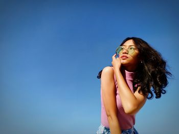 Low angle view of woman standing against blue sky