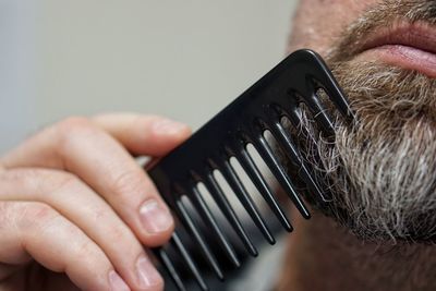 Close-up of man combing beard