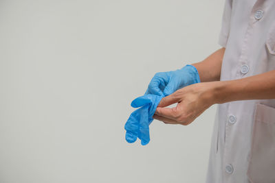 Midsection of woman holding hands against white background