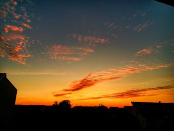 Silhouette trees against dramatic sky during sunset