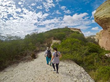 Rear view of women walking on mountain against sky