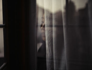 Close-up of woman looking through window