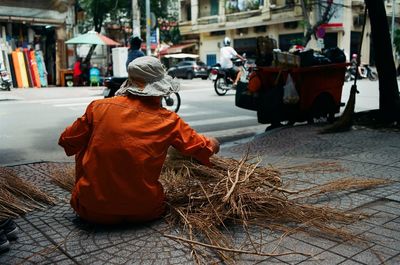 Rear view of man with twigs on street in city