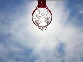 Low angle view of basketball hoop against cloudy sky during sunny day