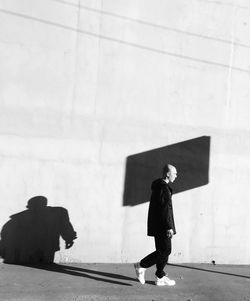 Side view of woman walking against wall