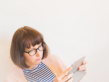 Young woman using mobile phone against white background