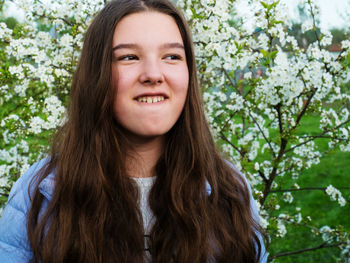 Girl making face while standing against flowering plant