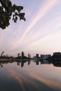 Scenic view of river by buildings against sky during sunset