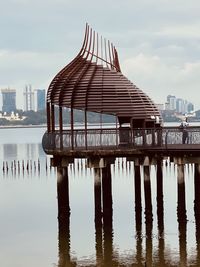 Pier over river against sky in city