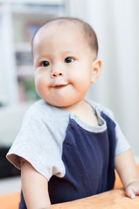 Close-up of toddler sitting on sofa at home