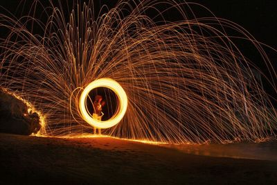 Woman standing by wire wool at night