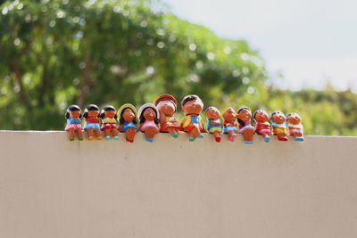 Close-up of human figurines in row on retaining wall outdoors
