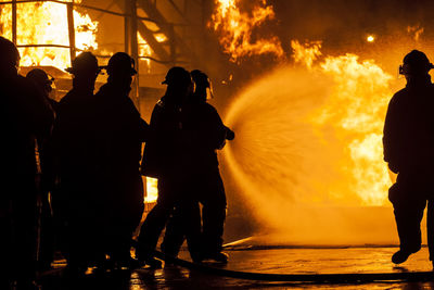 Firefighters spraying water on fire at night