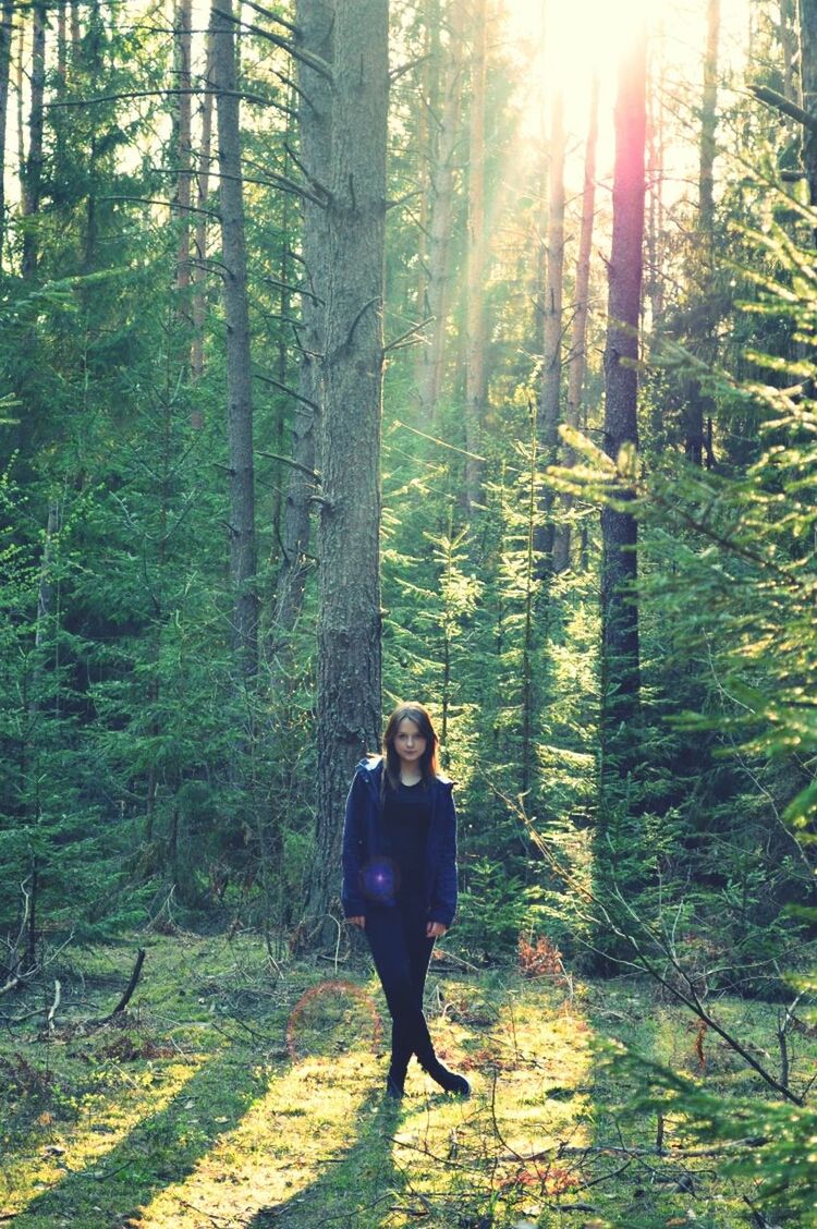 tree, forest, lifestyles, full length, tree trunk, woodland, leisure activity, standing, rear view, growth, sunlight, walking, nature, casual clothing, sunbeam, tranquility, day, outdoors