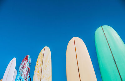 Low angle view of surfboards against blue sky