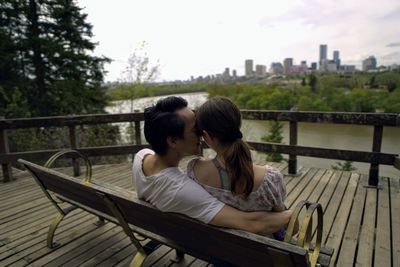 Friends sitting on railing against bridge