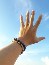 Close-up of hand against blue sky