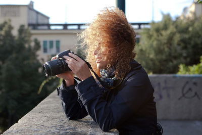 Close-up of young woman photographing on building terrace