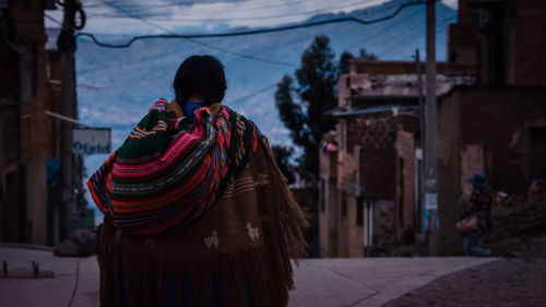 Rear view of woman walking against buildings in city