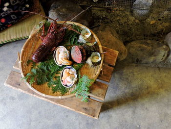 High angle view of seafood in wicker plate on wooden table at floor