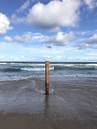 Wooden posts on beach against sky