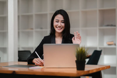 Portrait of a smiling young woman sitting on table