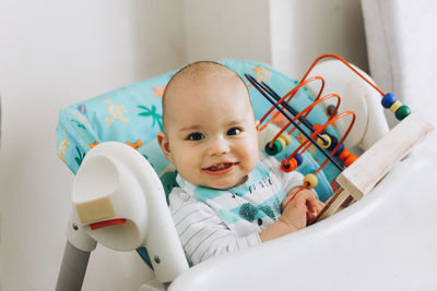 Portrait of cute baby sitting on stroller at home