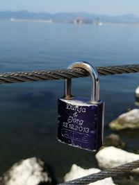Close-up of love padlocks hanging on metal by sea