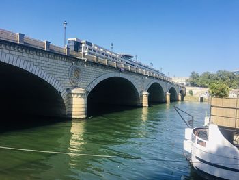 Arch bridge over river against clear sky