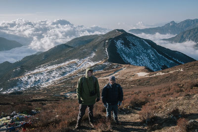 Rear view of people on snowcapped mountains against sky